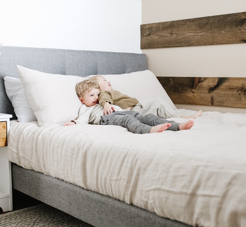 Two toddlers cuddle with enjoyment on their newly made Endy Upholstered Bed.